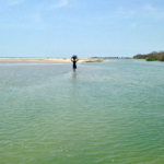 A fisherman in Tanji Village wades through a tidal pool